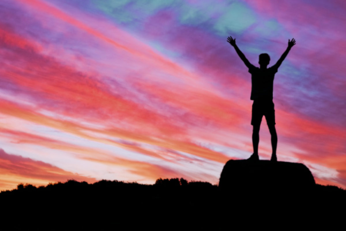 Silhouette of person celebrating victory in sunset
